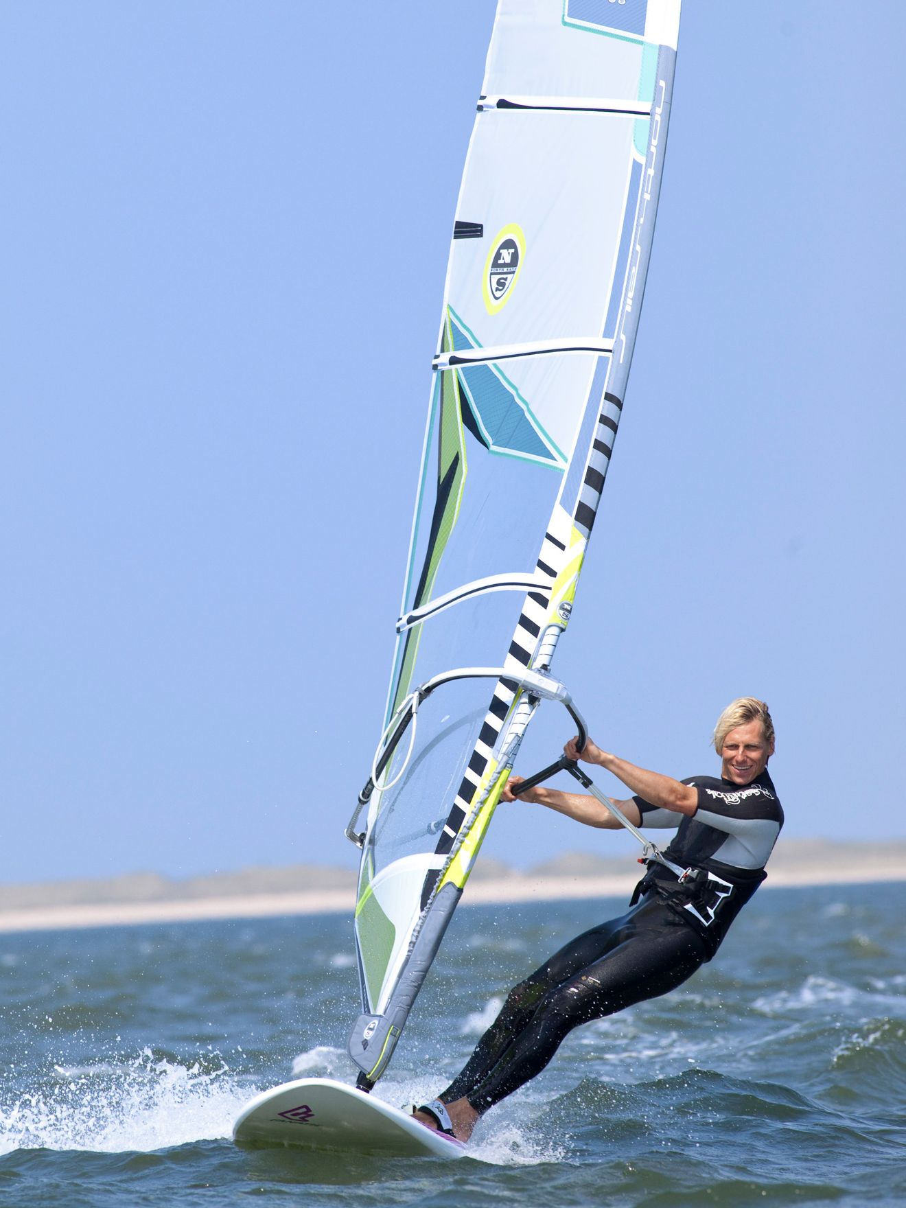 Wassersportlehrer auf einem Surfbrett im Wasser vor dem Hotel Strand
